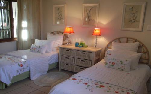 a bedroom with two beds and two lamps on top at Deck on Sea, 131 Nkwazi drive, Zinkwazi in Zinkwazi Beach