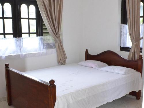 a bedroom with a bed with white sheets and windows at Sunset Beach Residence in Panadura