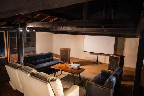 a living room with couches and a white screen at MAYUDAMAHOUSE in Higashiagatsuma