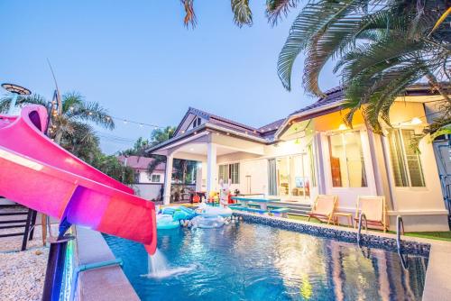 a pool with a slide in front of a house at Cool Cool บางเสร่พูลวิลล่า in Sattahip