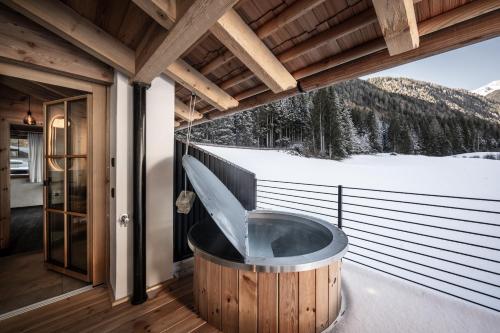 a jacuzzi tub on the balcony of a house at Valsegg Chalets Südtirol - luxury and private hideaway in Valles