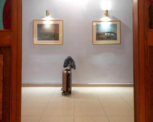 a suitcase in a room with two pictures on the wall at Hotel Avra in Kardítsa