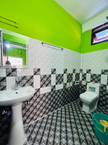 a green bathroom with a sink and a toilet at Kalden Homestay in Dirang Dzong