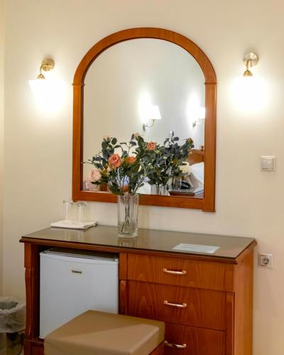 a bathroom with a mirror and a vase of flowers at Hotel Avra in Kardítsa