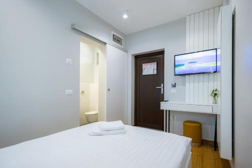 a bedroom with a white bed and a tv on the wall at RUTA 85 Hotel Restaurant in Iugani