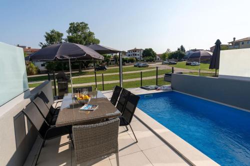 a patio with a table and chairs next to a pool at Casa Levant in Funtana