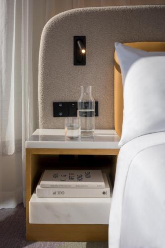 a nightstand next to a bed with a bottle on it at Mondrian Hong Kong in Hong Kong