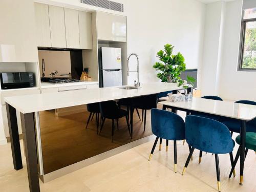 a kitchen with a large white counter and blue chairs at Charming and cozy 2 Bedrooms 2 bathrooms Condo with Study room, Parking, Wi-Fi in Sydney