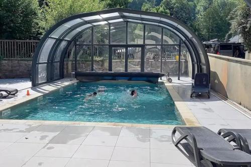 2 personnes se baignant dans une piscine dans une serre dans l'établissement T2 chaleureux St Lary village, à Saint-Lary-Soulan