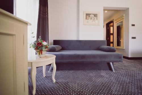 a living room with a blue couch and a table at Hotel Helen in Bacău