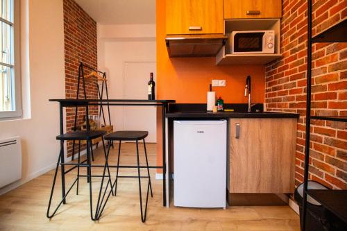 a kitchen with a bar with stools and a microwave at Studios Saint Jacques, Châtellerault in Châtellerault
