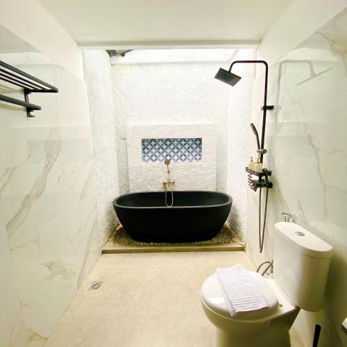 a bathroom with a black tub and a toilet at Fulton Avalon 3BR in Ngaglik
