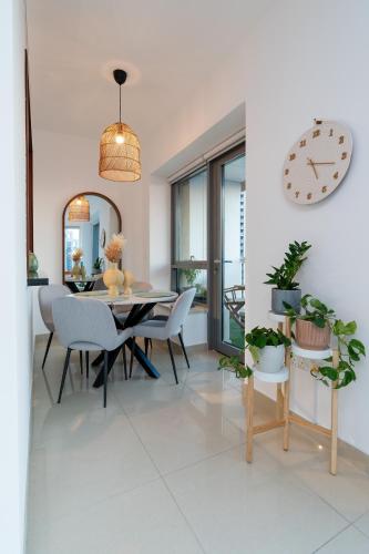 a dining room with a table and chairs and a clock at Luxury High Floor 1BR with Full Burj Khalifa View by Auberge in Dubai