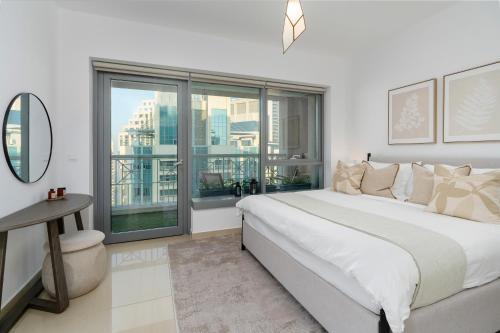 a white bedroom with a large bed and a window at Luxury High Floor 1BR with Full Burj Khalifa View by Auberge in Dubai