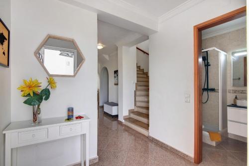 a hallway with white walls and a mirror and stairs at Villa Martina in Albufeira