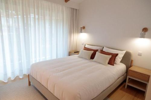 a bedroom with a large white bed with two pillows at Dalpendre - Turismo em espaço rural in Felgueiras
