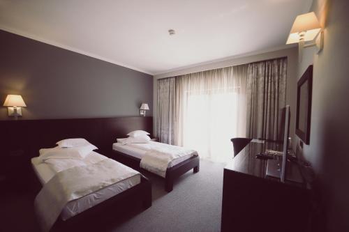 a hotel room with two beds and a television at Hotel Helen in Bacău
