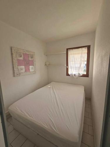 une petite chambre avec un lit blanc et une fenêtre dans l'établissement Cap d'Agde bord de mer, au Cap d'Agde
