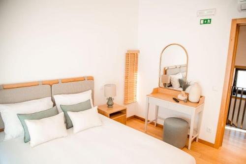 a bedroom with a bed and a table with a mirror at Dalpendre - Turismo em espaço rural in Felgueiras