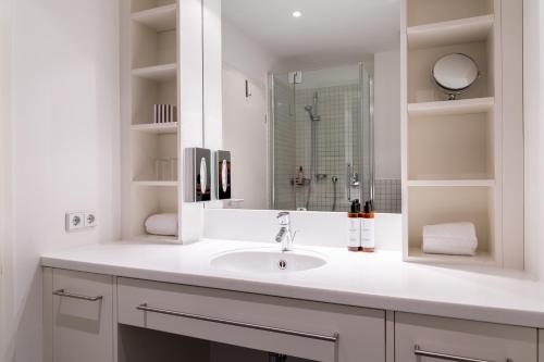 a white bathroom with a sink and a mirror at Hotel Alma Am Anger in Erfurt