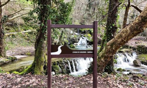 a sign in front of a waterfall in a forest at Dalpendre - Turismo em espaço rural in Felgueiras