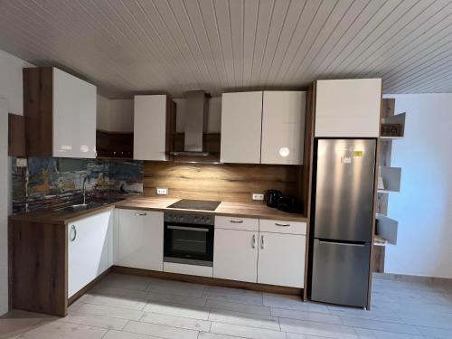 a kitchen with white cabinets and a stainless steel refrigerator at Ferienwohnung Steinlicht in Lienz