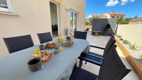 une table avec de la nourriture dessus sur une terrasse dans l'établissement LE CABES - 2 Chambres - Climatisation - BBQ -Terrasse - Wifi - Bureau - SudSéjourConciergerie, à Cabestany