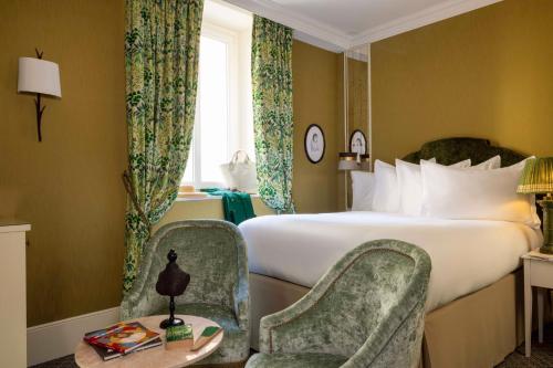 a hotel room with a bed and two chairs at UNE AUTRE CHAMBRE in Paris