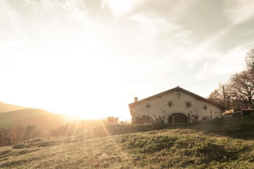 a house on a hill with the sun in the sky at Olabe in Ea