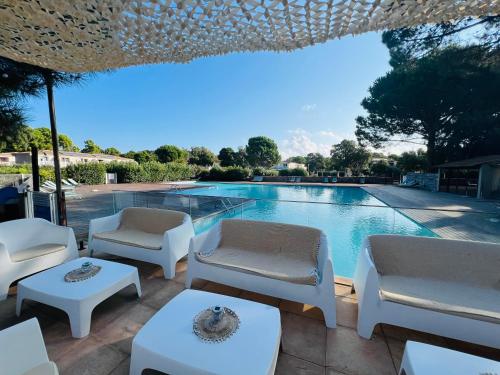 - une piscine avec des chaises blanches et une table dans l'établissement Location T2 44 m2 proche plage Lecci appartement 82, à Lecci