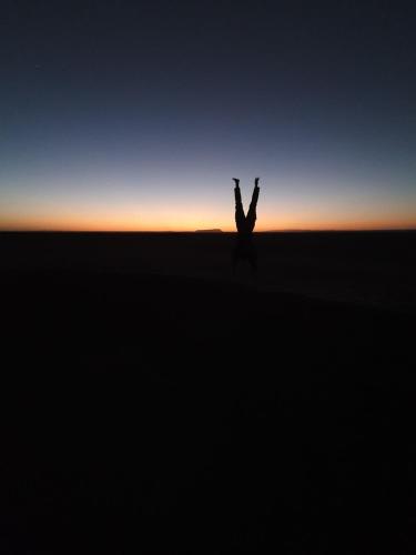 a person with their arms in the air at sunset at Bivouac Les Nomades & Foum zguid to chegaga tours in Foum Zguid