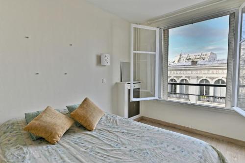 une chambre avec un lit et une grande fenêtre dans l'établissement Appartement Central Avenue du Maine - II, à Paris