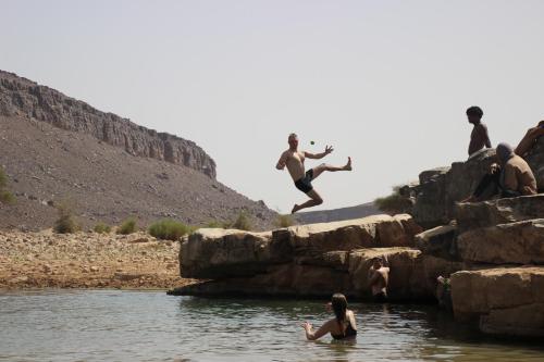 a group of people jumping off rocks into a river at Bivouac Les Nomades & Foum zguid to chegaga tours in Foum Zguid
