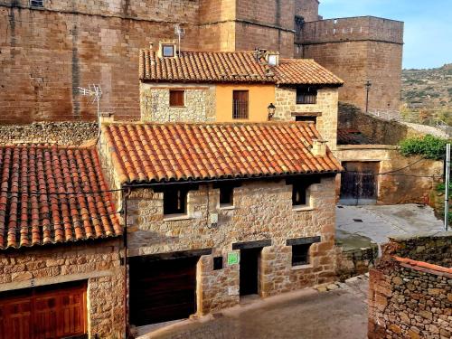 an old stone building with a castle in the background at Casa Rural El Secreto del Castillo in Mora de Rubielos