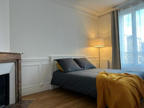 a bedroom with a bed with a fireplace and a window at Charmant 2 pièces à deux pas de Paris in Saint-Maurice