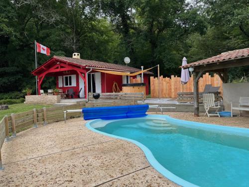 - une piscine en face d'une petite maison dans l'établissement Le chalet Canadien, à Saint-Laurent-des-Hommes