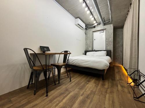 ein Schlafzimmer mit einem Bett und einem Tisch und Stühlen in der Unterkunft THE BEDROOM Daimyo in Fukuoka