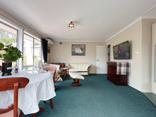 a room with a table and chairs and a living room at Kings Corner - 5min to CBD & 20min to Airport in Sandy Bay