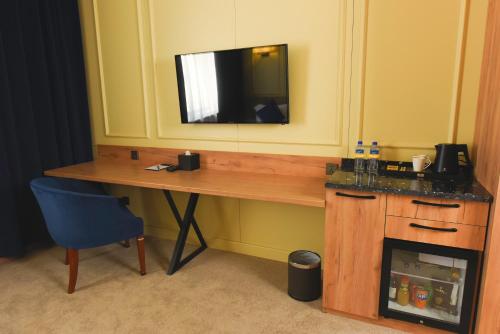 a desk with a television and a blue chair at Ulaanbaatar Hotel in Ulaanbaatar