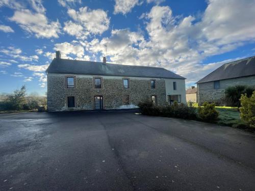a large brick building with a driveway in front of it at Maison des H, au bord de l'Etang in Canisy