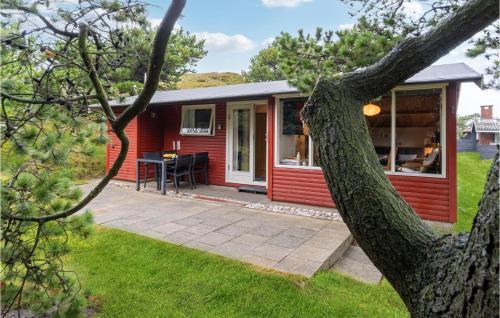 czerwony domek z patio w trawie w obiekcie Holiday Home Østre Klitvej Fanø Xii w mieście Fanø