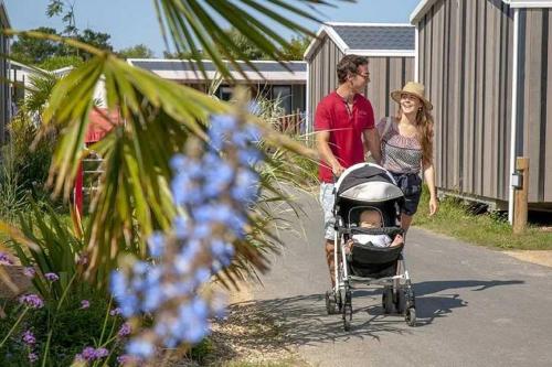 a man and a woman walking with a baby in a stroller at Camping 5 étoiles - Parc aquatique - eeiade in Brem-Sur-Mer