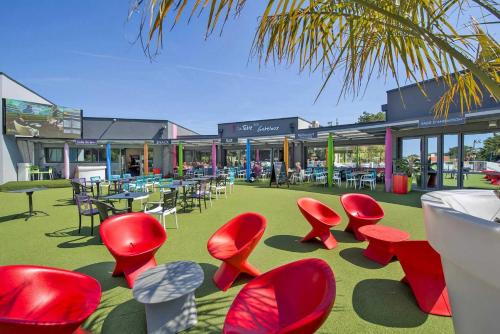 a group of red chairs and tables in front of a building at Camping 5 étoiles - Parc aquatique - eeiade in Brem-Sur-Mer