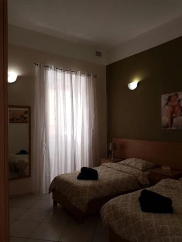 a hotel room with two beds and a window at Central Valletta Apt by Castille Square in Il-Furjana