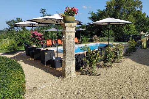 a stone pillar with umbrellas and a swimming pool at DORDOGNE 24 Chambre d'hôtes Jardin d'hiver Élégance Champêtre pour un séjour in Rouffignac Saint-Cernin