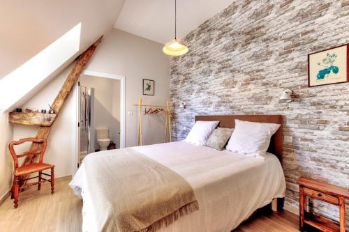 une chambre avec un grand lit et un mur de briques dans l'établissement DORDOGNE 24 Chambre d'hôtes CAMPAGNARDE Élégance Champêtre pour un séjour romantique, à Rouffignac-Saint-Cernin-de-Reilhac