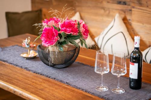 a table with a vase with pink flowers and wine glasses at Chalet Hoamat Leben in Leogang