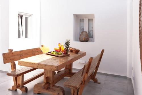 a wooden table with two benches and a bowl of fruit at Villa Izabela in Santorini