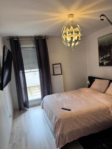 une chambre avec un lit et un lustre dans l'établissement appartement, à Dijon
