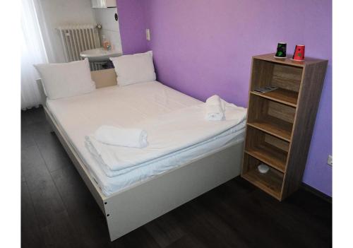 a bed in a small room with a small shelf at Hotel Annis M&P in Dortmund